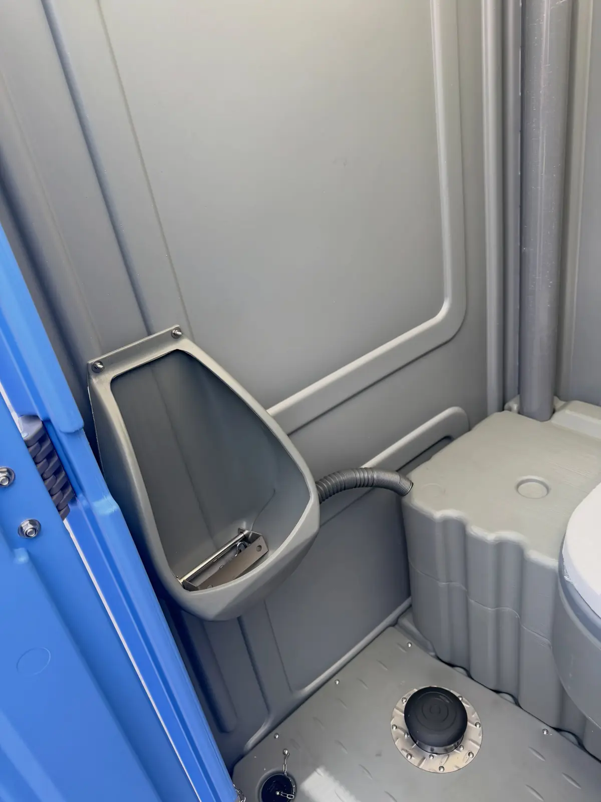 Urinal mounted on the side wall of a standard porta potty