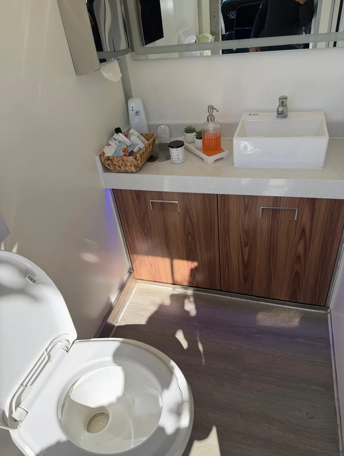Wood-finish vanity with white basin inside a restroom trailer
