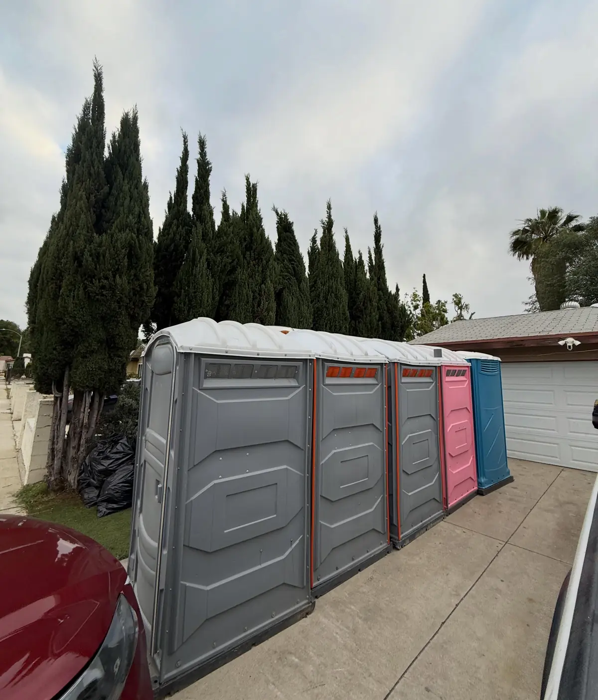 Row of portable toilets in several colors on a driveway